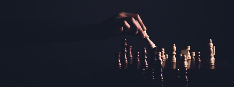 dłoń przesuwająca pionki na szachownicy
